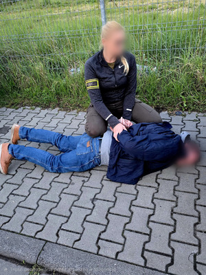 policjantka kuca nad zatrzymanym.
