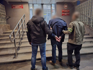 dwóch policjantów stoi z zatrzymanym.
