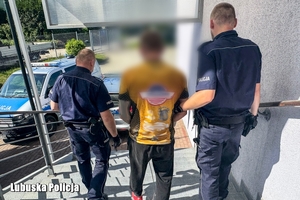 Dwaj policjanci prowadzą zatrzymanego.