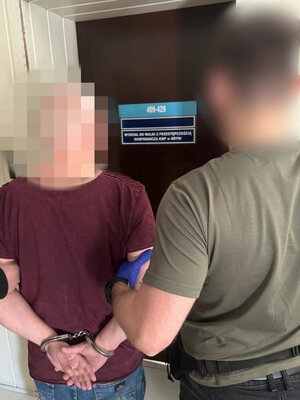 Policjant z zatrzymanym przed drzwiami.