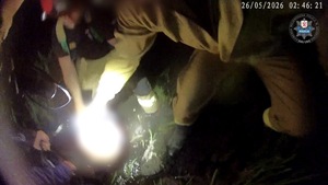 Policjant ze strażakami wyciągają z wody mężczyznę.