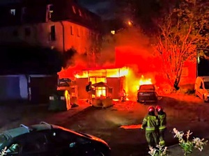 Paląca się wiata śmietnikowa i samochód.