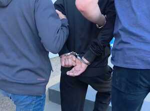 Zatrzymany mężczyzna prowadzony przez policjantów.