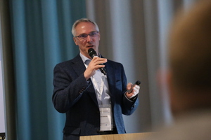 Prelegent z mikrofonem podczas wystąpienia na konferencji.
