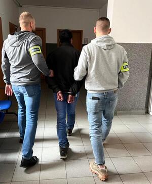 Dwaj policjanci prowadzą zatrzymanego.
