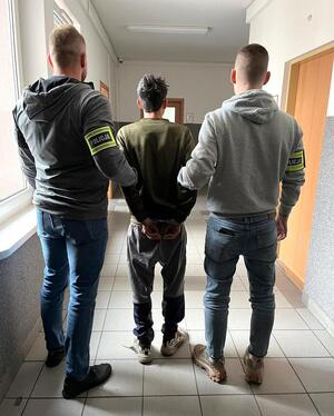 Dwaj policjanci prowadzą zatrzymanego.