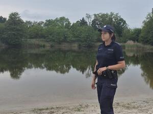policjantka stoi na brzegu obok wody.