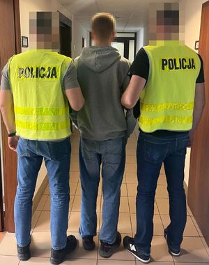 dwóch policjantów prowadzi zatrzymanego.