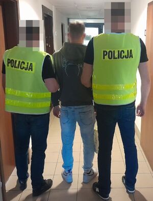 dwóch policjantów prowadzi zatrzymanego.