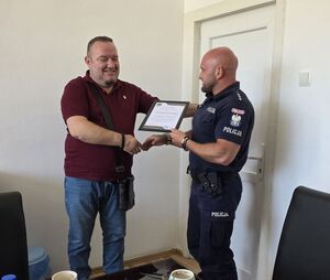 Mężczyzna z policjantem będą ściskać sobie wzajemnie dłonie.