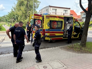 Policjanci stoją przy karetce pogotowia.