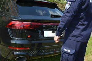 Policjant przy bagażniku auta.