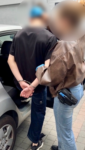 policjantka prowadzi zatrzymanego.