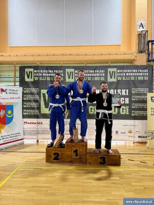 Podkomisarz Maciej Iwoła z Centralnego Laboratorium Kryminalistycznego Policji i dwaj inni zawodnicy na podium.