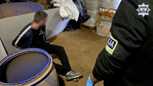 Zatrzymany mężczyzna i widoczny fragment rękawa policjanta z naszywką "Policja".