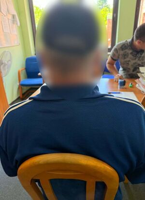 Zatrzymany mężczyzna siedzi na krześle - widok z tyłu.
