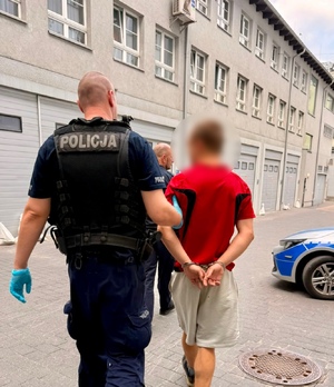 policjant prowadzi zatrzymanego.