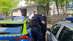 policjant prowadzi zatrzymanego.