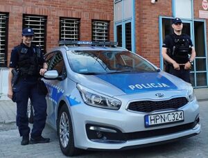 Dwóch policjantów przy radiowozie.