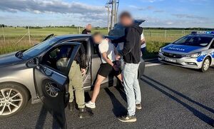 Policjanci z zatrzymanym przy samochodzie.