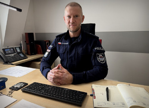Policjant siedzi za biurkiem.