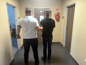 policjant stoi z zatrzymanym.