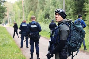 policjanci stoją na drodze leśnej.
