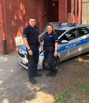 Dwoje policjantów przy radiowozie.