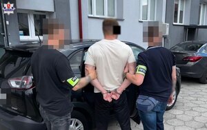 Dwaj policjanci prowadzą zatrzymanego.