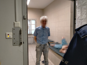 Zatrzymany mężczyzna w pomieszczeniu z kratami.