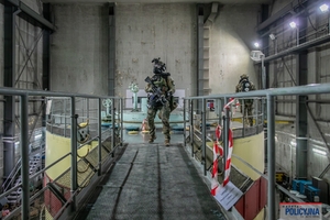 Dwaj funkcjonariusze podczas ćwiczeń. Na głowach mają kaski, w rękach trzymają karabiny.