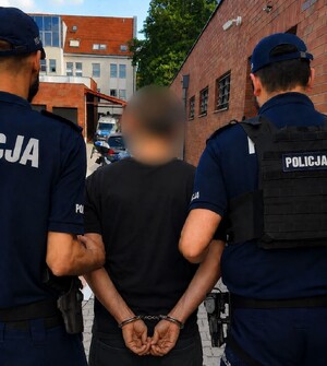 Dwaj policjanci prowadzą zatrzymanego.