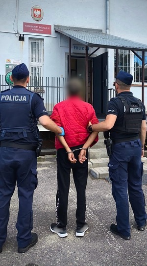 dwóch policjantów prowadzi zatrzymanego.