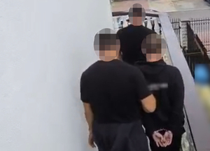 Policjanci prowadzą zatrzymanego - widok z tyłu.