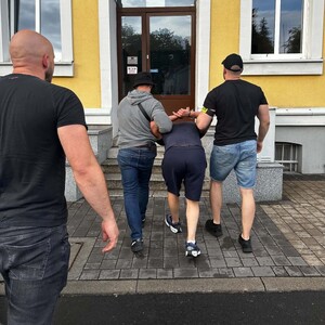 Policjanci wprowadzają zatrzymanego do budynku.