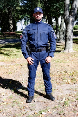Policjant w nowym umundurowaniu. Na głowie ma czapkę typu bejsbolówka.