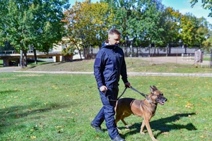 Policjant w nowym umundurowaniu prowadzi psa na smyczy.
