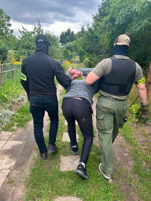 Dwaj policjanci prowadzą zatrzymanego.