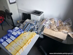 Zabezpieczone paczki papierosów i woreczki z tytoniem leżące na stole.