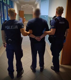 Dwaj policjanci prowadzą zatrzymanego.