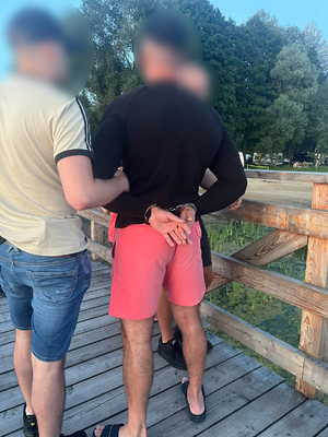 Dwaj policjanci trzymają zatrzymanego mężczyznę.