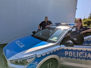 Dwoje policjantów przy radiowozie.