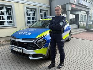 policjantka stoi przed radiowozem.