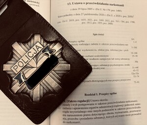 Odznaka policyjna leży na otwartym kodeksie karnym.