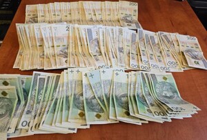 Banknoty 100 i 200-złotowe leżą na blacie.