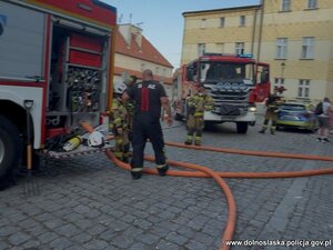 Wozy straży pożarnej i strażacy na miejscu zdarzenia.