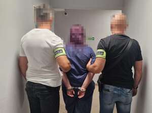 Policjanci prowadzą zatrzymaną.