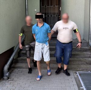 dwóch policjantów prowadzi zatrzymanego.