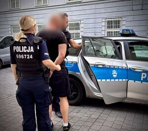 policjanci prowadzą zatrzymanego do radiowozu.