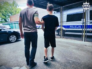policjant stoi z zatrzymanym.